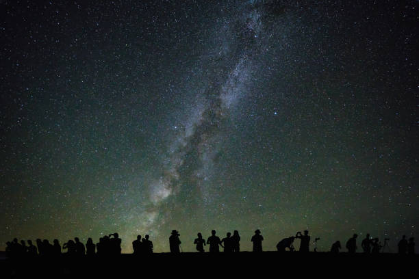 A large group of people is watching the stars and the milky way from Zabriskie Point in Death Valley (digitally enhanced).