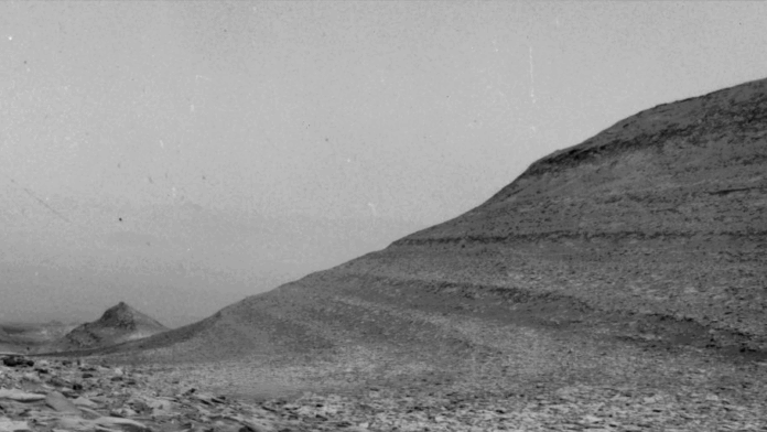 A grainy black-and-white image of a distant hill captured by NASA's Curiosity Mars rover shows specks caused by charged particles from a solar storm hitting one of its navigation cameras. The rover uses these cameras to capture images of dust devils and wind gusts, as seen in this sequence. (Image credit: NASA/JPL-Caltech)